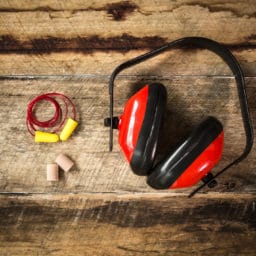 Earplugs and Ear Protection laid out on a wooden style background