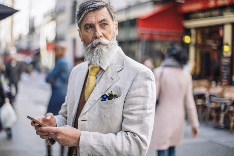 Older gentleman with a single hearing aid holding a cellphone