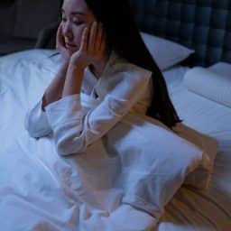 Woman with insomnia sitting up in bed at night.