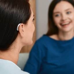 Young woman with a hearing aid chats with her friend.