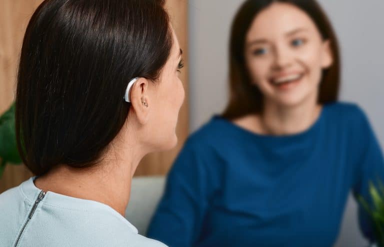 Young woman with a hearing aid chats with her friend.