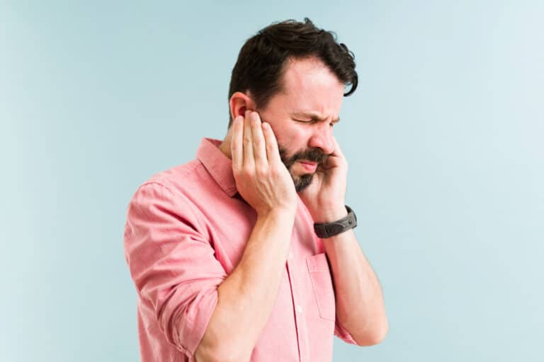 Man with tinnitus holding his ears