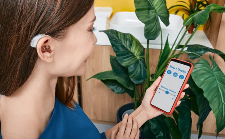 Woman adjusting her hearing aid programming on her phone