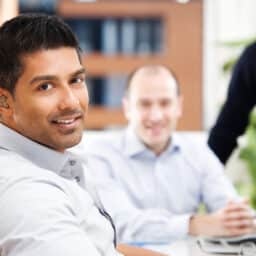 Smiling man wearing a hearing aid sitting with friends