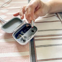 Senior man removing hearing aid from charging case