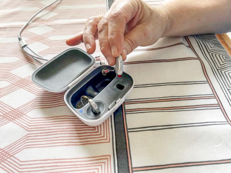 Senior man removing hearing aid from charging case